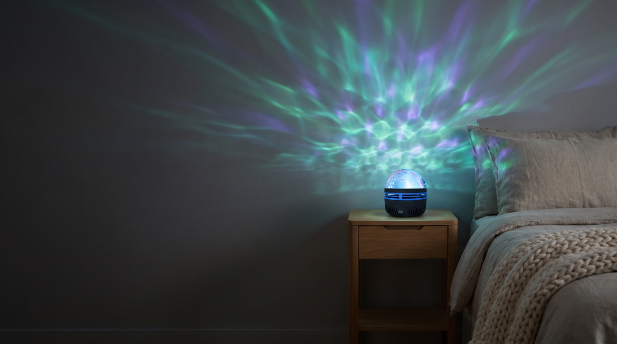 Dark bedroom lit by soft green and violet northern-lights patterns from the small Norrsken lamp on the nightstand